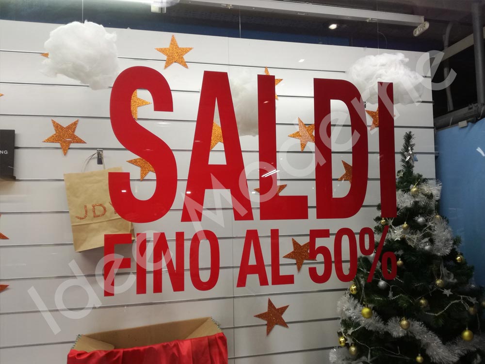 Applicazione scritte saldi e offerte su vetrina negozio