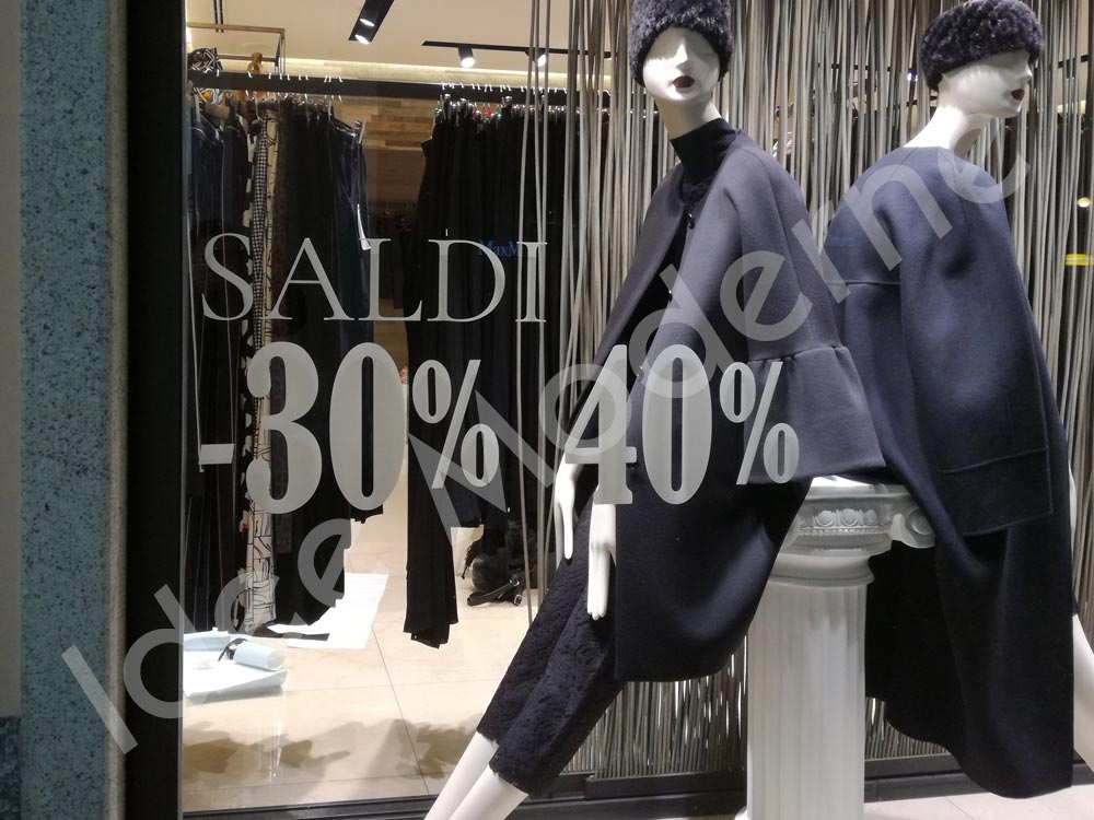 Applicazione scritte saldi e offerte su vetrina negozio