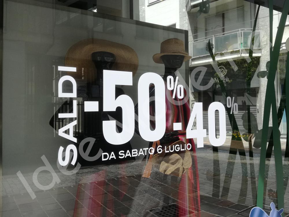 Applicazione scritte saldi e offerte su vetrina negozio