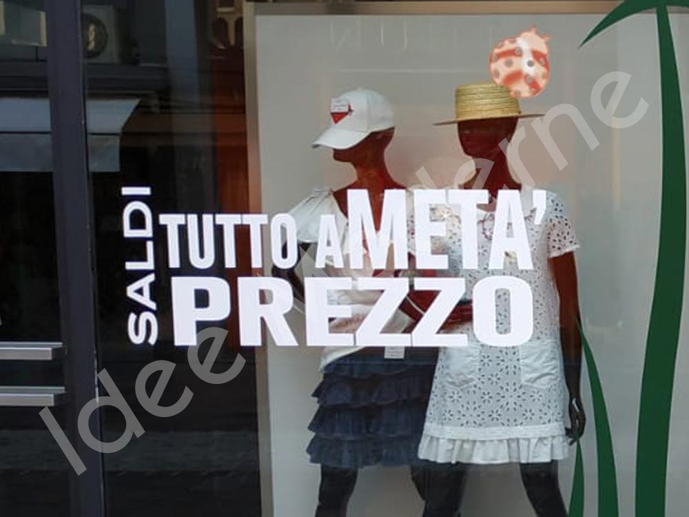 Applicazione scritte saldi e offerte su vetrina negozio