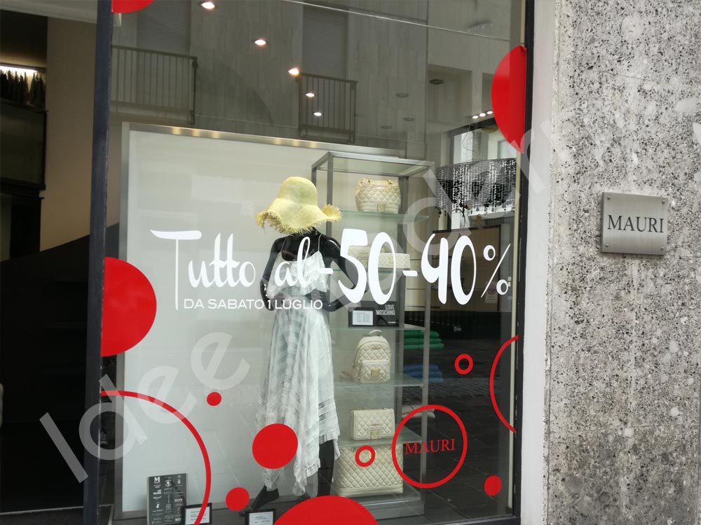 Scritte promozionali saldi stagionali su vetrina negozio