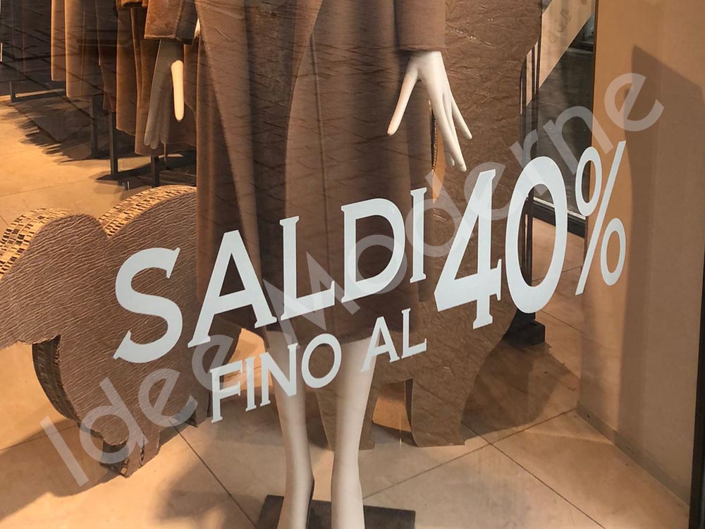 Applicazione scritte saldi e offerte su vetrina negozio