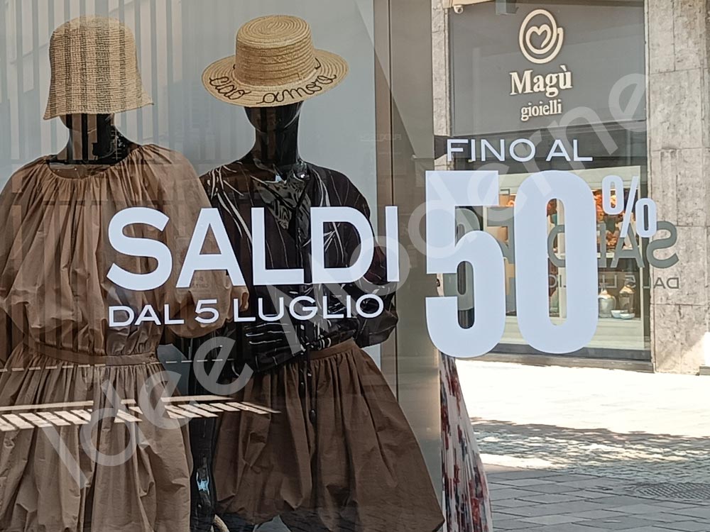 Applicazione scritte saldi e offerte su vetrina negozio