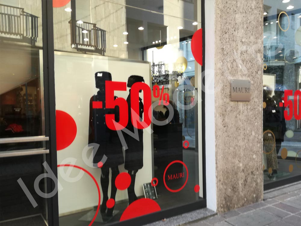 Scritte promozionali saldi stagionali su vetrina negozio