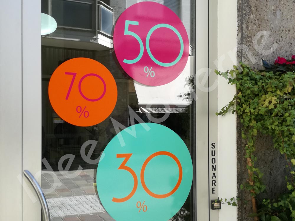 Scritte promozionali saldi stagionali su vetrina negozio