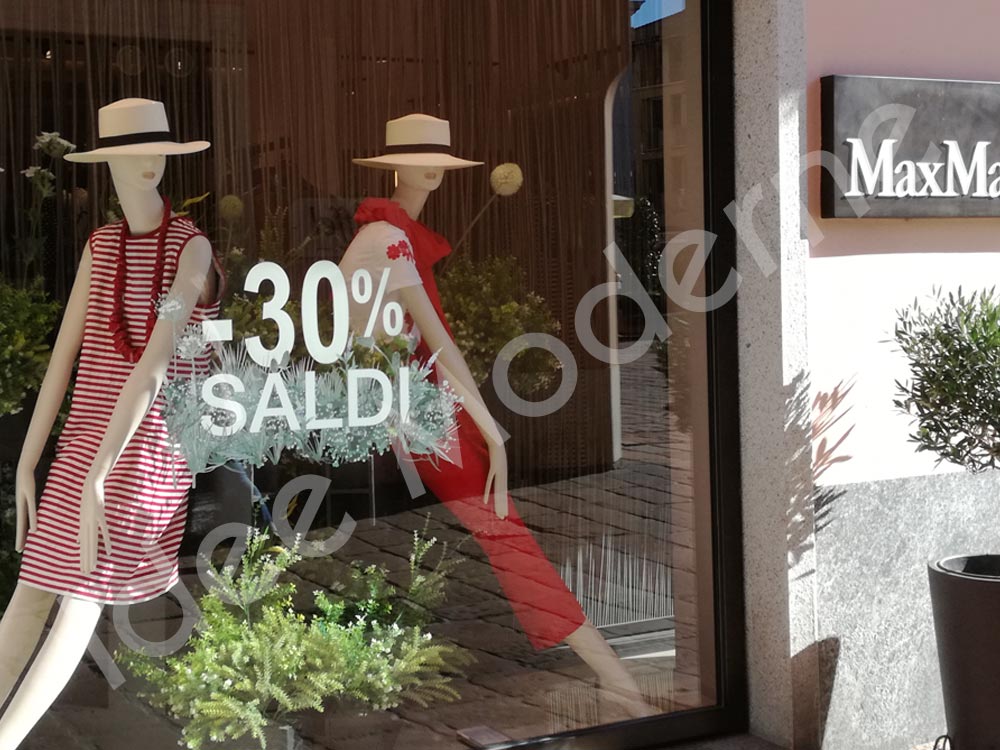 Scritte promozionali saldi stagionali su vetrina negozio
